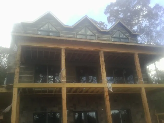 Dormers and porch framing on a large log home under construction — Roof Coating work by our crew in Plainview