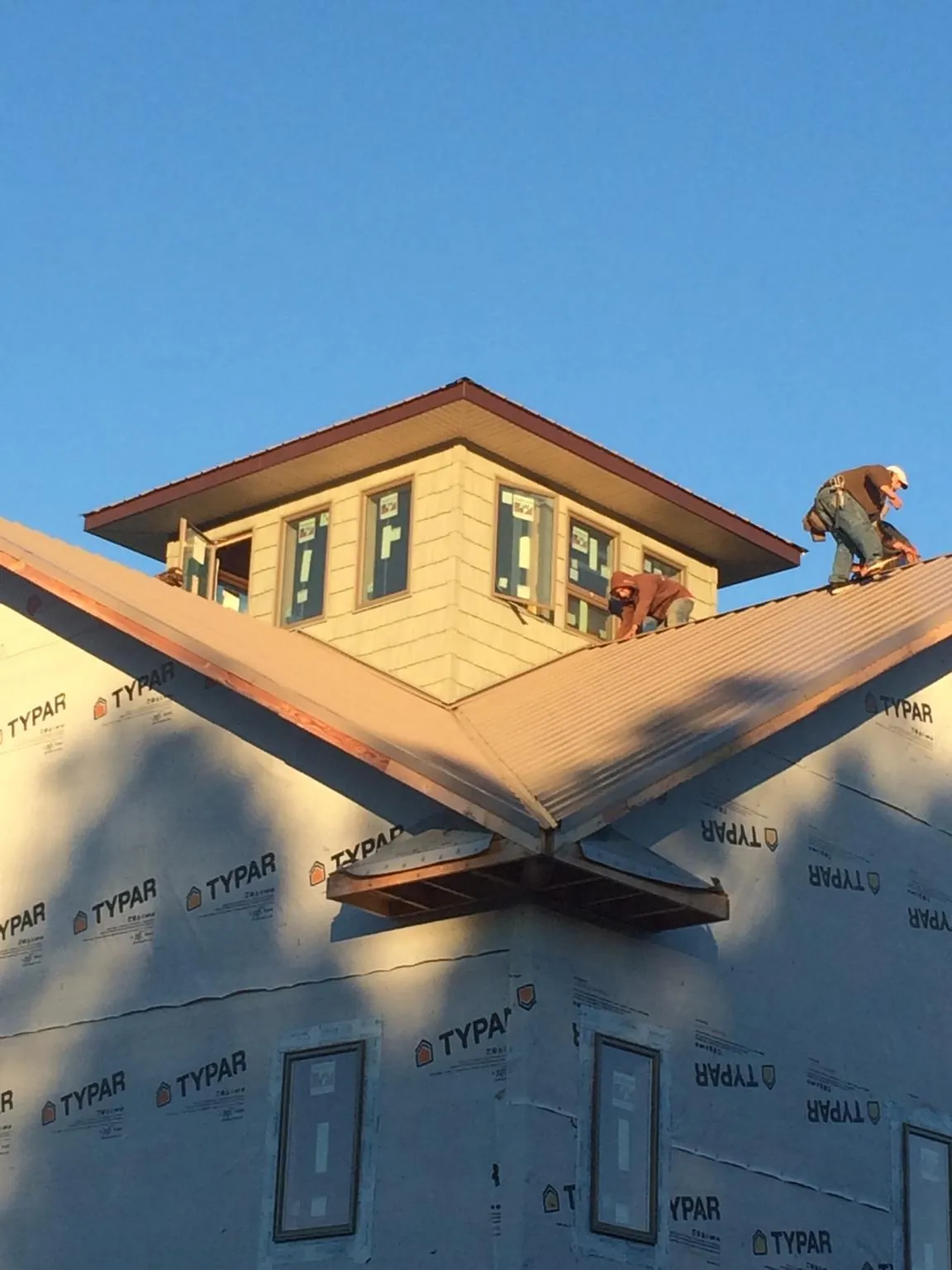 Roofers working around a rooftop cupola on a new metal roof at sunset — Roof Waterproofing in Plainview by Roofing Brothers
